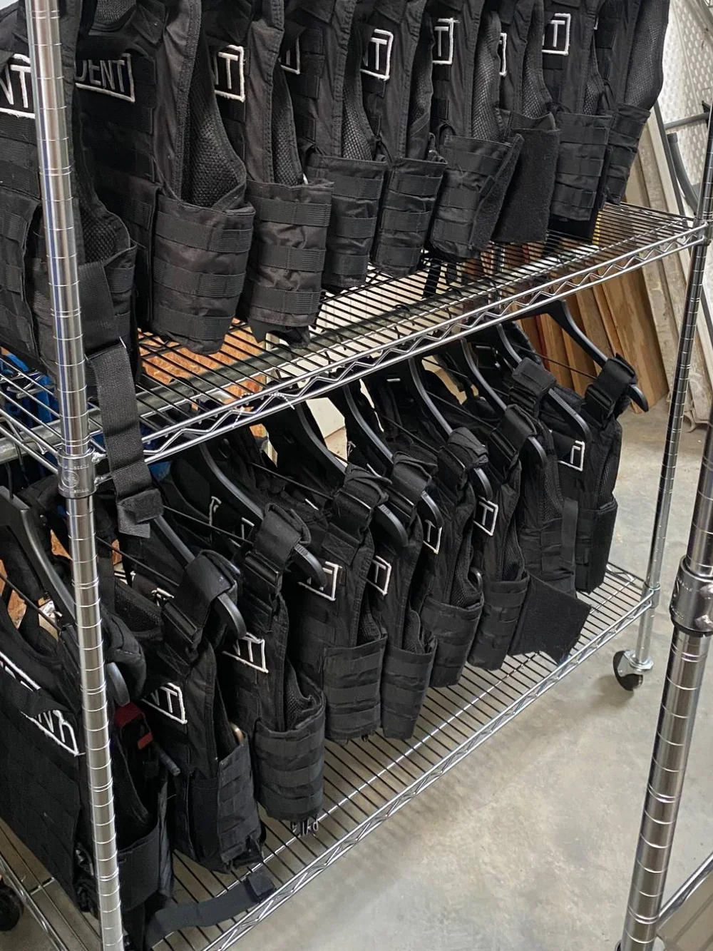 Rows of black plate carriers labelled STUDENT, hung on a rolling wire rack.